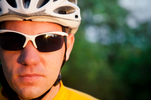 Close up portrait of male caucasian professional cyclist with lots of copy space. About 25 years old, Caucasian male with helmet and glasses.