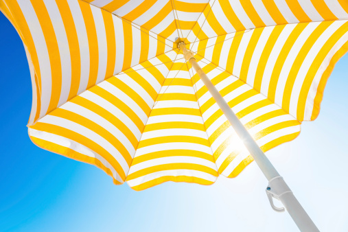 Beach umbrella against blue morning sky.