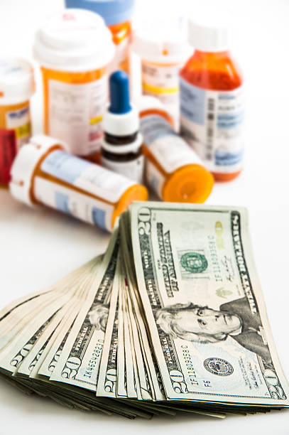 pile of 20 dollar bills and medicine containers on white background