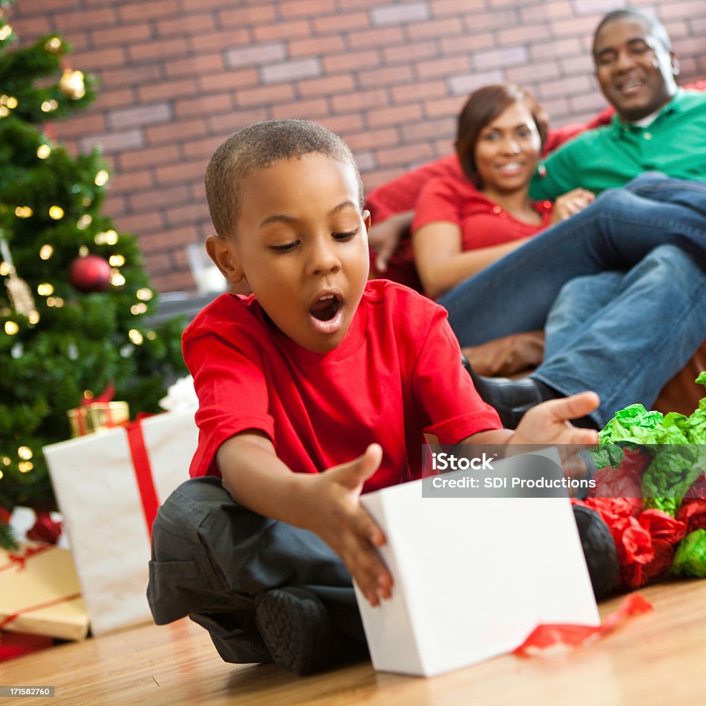 Suprised little boy opening present on Christmas morning Suprised little boy opening present on Christmas morning. Gift Stock Photo