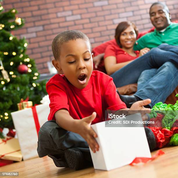 Suprised Little Boy Opening Present On Christmas Morning Stock Photo - Download Image Now