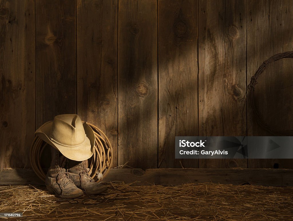 Western packer to buty, kapelusz i lasso na barn podłogi Promień słońca na barnwood ściany - Zbiór zdjęć royalty-free (Stodoła)