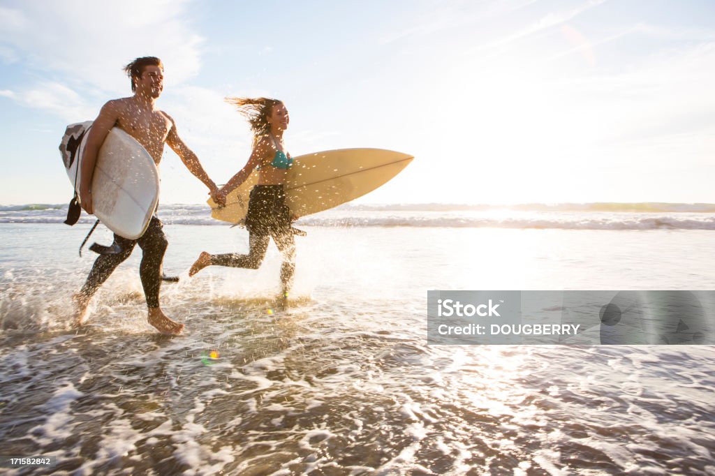 Couple Running Through The Surf Stock Photo - Download Image Now - Surfing,  Couple - Relationship, Beach - iStock