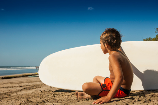 A young surfer relaxing on the beach in Costa Rica with his board.For more beach related images please click: