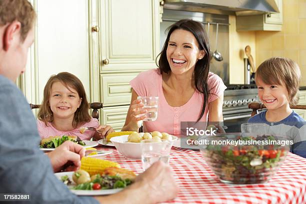 A Happy Family Sharing A Meal In The Kitchen Stock Photo - Download Image Now - Eating, Corn, Two Parents