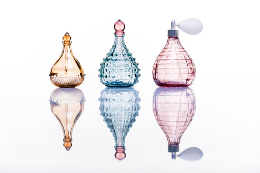 Bottom view of one spray bottle of perfume stands on a glass table.