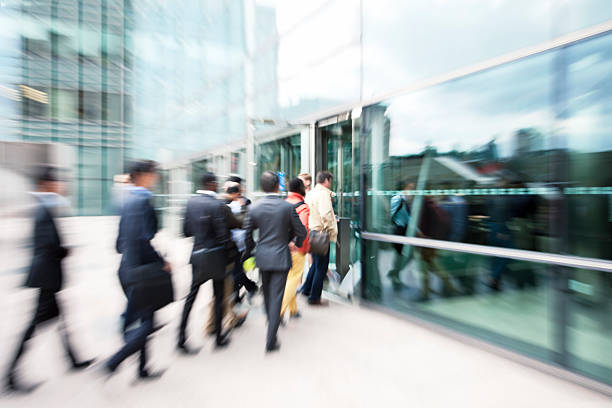 blurred business people entering office building through glass doors - girmek stok fotoğraflar ve resimler