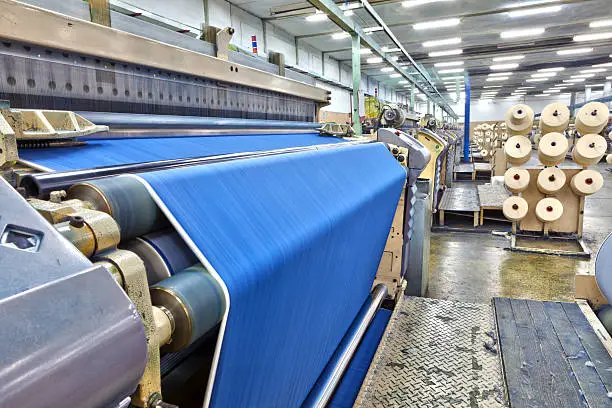 Weaving fabric on air jet looms in big textile weaving unit.
