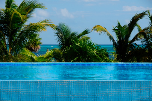 Telephoto image of a hotel luxury infinity pool with the caribbean in the background.