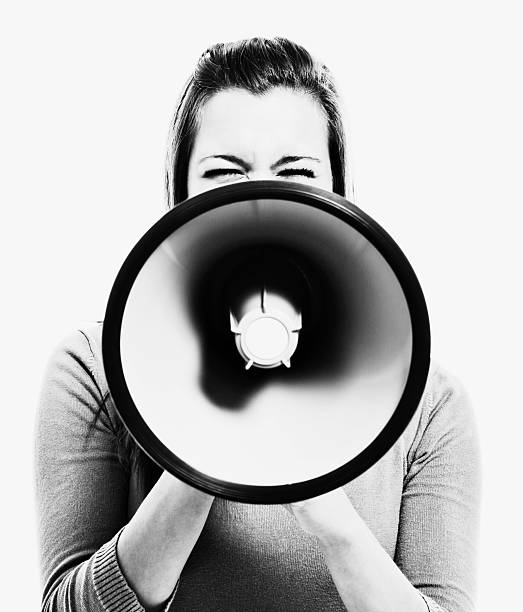 Woman obscured by megaphone she holds MoniqueA young woman is almost obscured by the big bullhorn she is holding up in front of her. public address system stock pictures, royalty-free photos & images