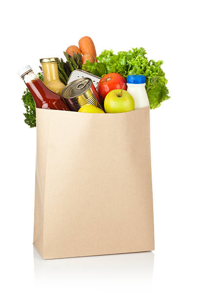 brown paper shopping bag full of groceries on white backdrop - boodschappen stockfoto's en -beelden