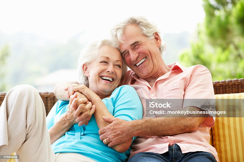 Senior Couple Sitting On Outdoor Seat Together Senior Couple Sitting On Outdoor Seat Together Laughing Senior Couple Stock Photo