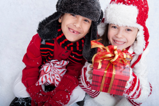 Young 8 year old boy and 7 year old girl holding presents