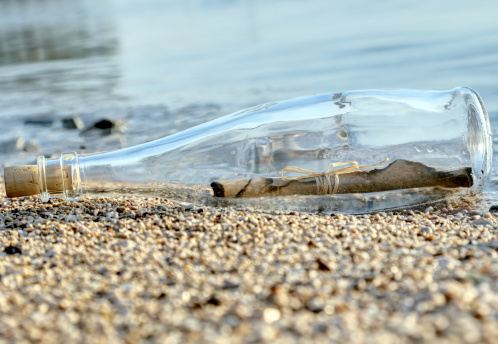 Bottle with a message aground on a sandy beach