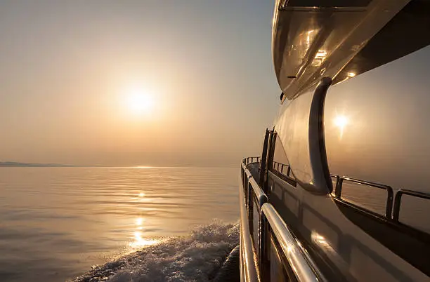 Luxury motor yacht sailing at sunset. Moody atmosphere. Diminishing perspective.NOTE: Intentionally underexposed in order to get a moody atmosphere and a nice sun light. More of yachting in this lightboxes