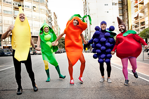 Five men dressed up like vegetables running in the street