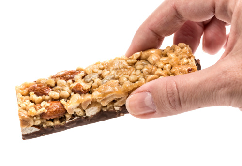 Woman hand holding an energy bar on white background