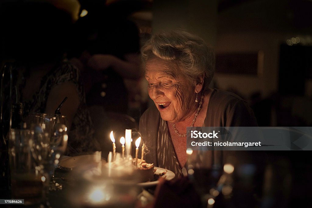 Elderly Lady:  Birthday Celebration Happy 85 year old woman ready to blow out birthday candles.  High level of noise, due to low light.More senior lady lifestyle shots: Birthday Stock Photo