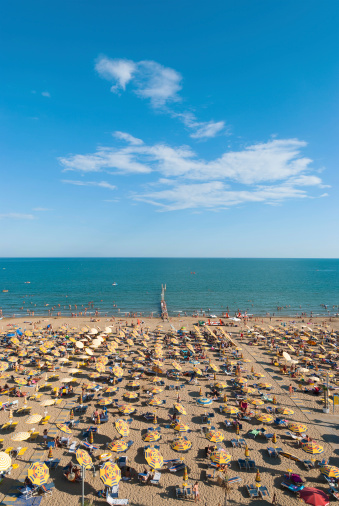 Wonderful capture of venetian beach on a sunny afternoon. Jesolo, Caorle, Lignano, Rimini, Bibione Beach. All human faces and brands are well blurred and not recognizable, so you can use it for commercial purposes. Cyan blue ocean and light blue sky. Well post-processing.