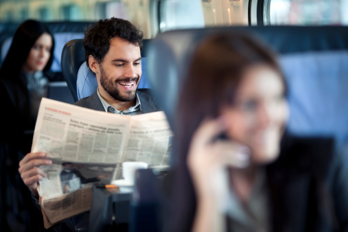Business travel by train. Businessman reading  Newspaper  on a Train  and smiling
