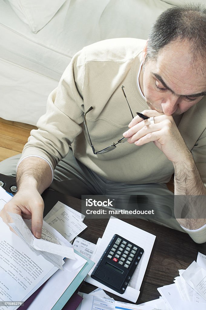 Man doing tax report at home. Mature man doing his annual tax report in his living room. Financial Advisor Stock Photo