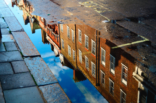 building reflected in roadside puddle
