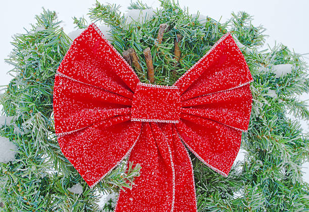 A red Chistmas bow on evergreens and covered with a light frost.