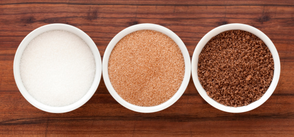 Top view of three bowls containing sugar varieties (white, brown and black)