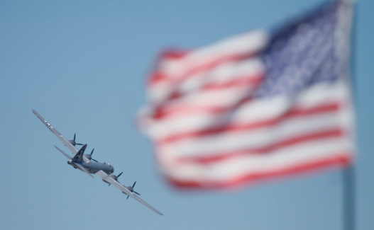 The only remaining airworthy B-29 Superfortress bomber flys past an American Flag. The B-29 was flown during World War 2 and carried a crew of 10 airmen.