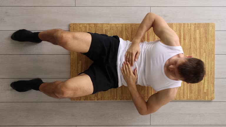 Handsome young man is engaged in fitness at home on rug shakes press