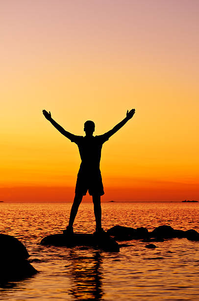 istock Young man with outstretched arms, sunset lake scenery - XI 171586136
