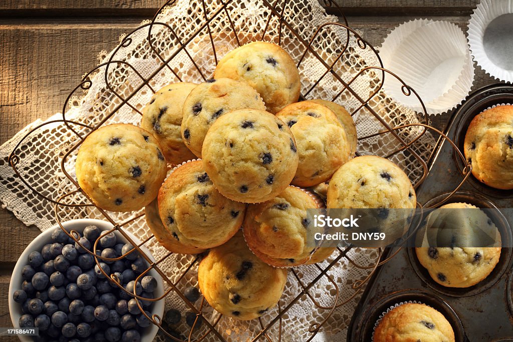 Blueberry Muffins Blueberry muffins in a wire basket with a bowl of blueberries and a muffin tray full of blueberries Blueberry Muffin Stock Photo