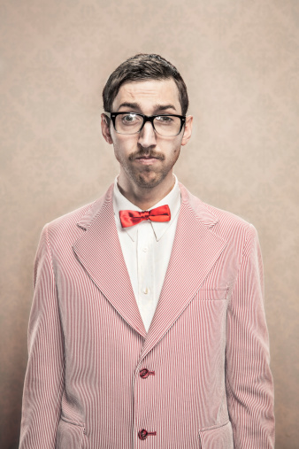 A retro styled image of a nerdy dorky man wearing a red and white suit and silk bow tie.  He has Horn-Rimmed glasses, mustache, and combed hair.
