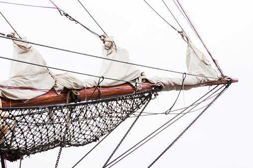 Closeup end of old sailing ship bowsprit agains white background, full frame horizontal composition with copy space