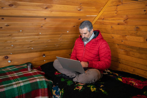 istock Cabin getaway. Man with laptop in log cabin. 1715870418