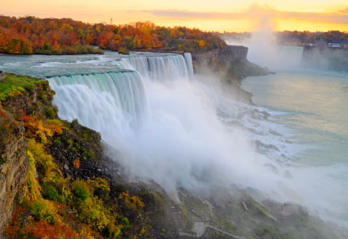 Niagara Falls with fall colors at sunset, viewed from New York side. Some motion blurs from the plants may be visible due to the wind and not focus issue.