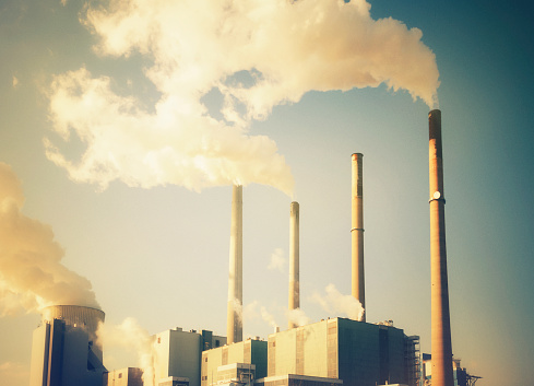 Power station with smoking chimneys in 70's retro look. Toned image with added grain.