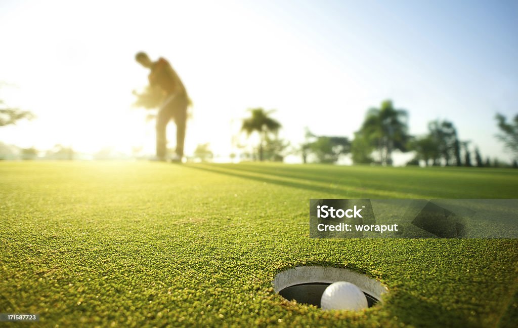 Morning putt Closeup of golf ball sinking a putt. Golf Stock Photo