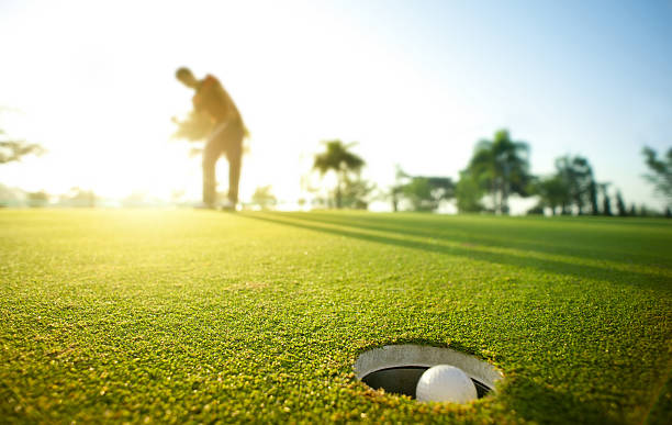 Morning putt Closeup of golf ball sinking a putt. putting green stock pictures, royalty-free photos & images