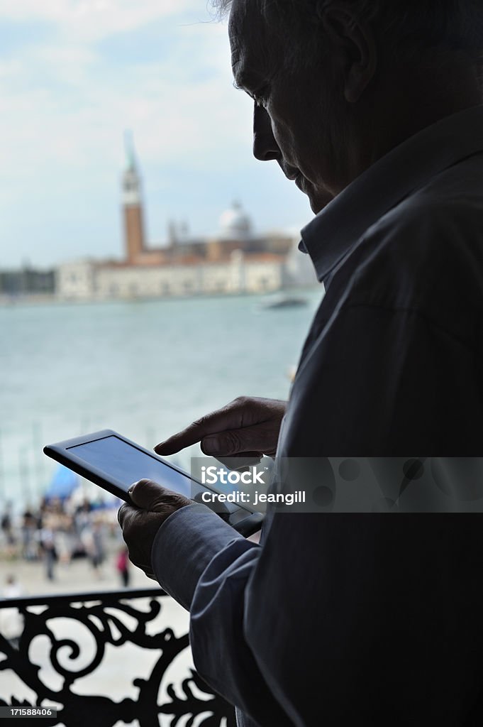 Using digital tablet in Venice Communication/reading while travelling on business or pleasure - man in silhouette with digital tablet and St Maggiore, Venice, in the background.More like this Venice - Italy Stock Photo