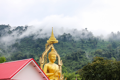 Nakhon Nayok ,Thailand. pictures of big Buddha gold color in temple with mountain background.
