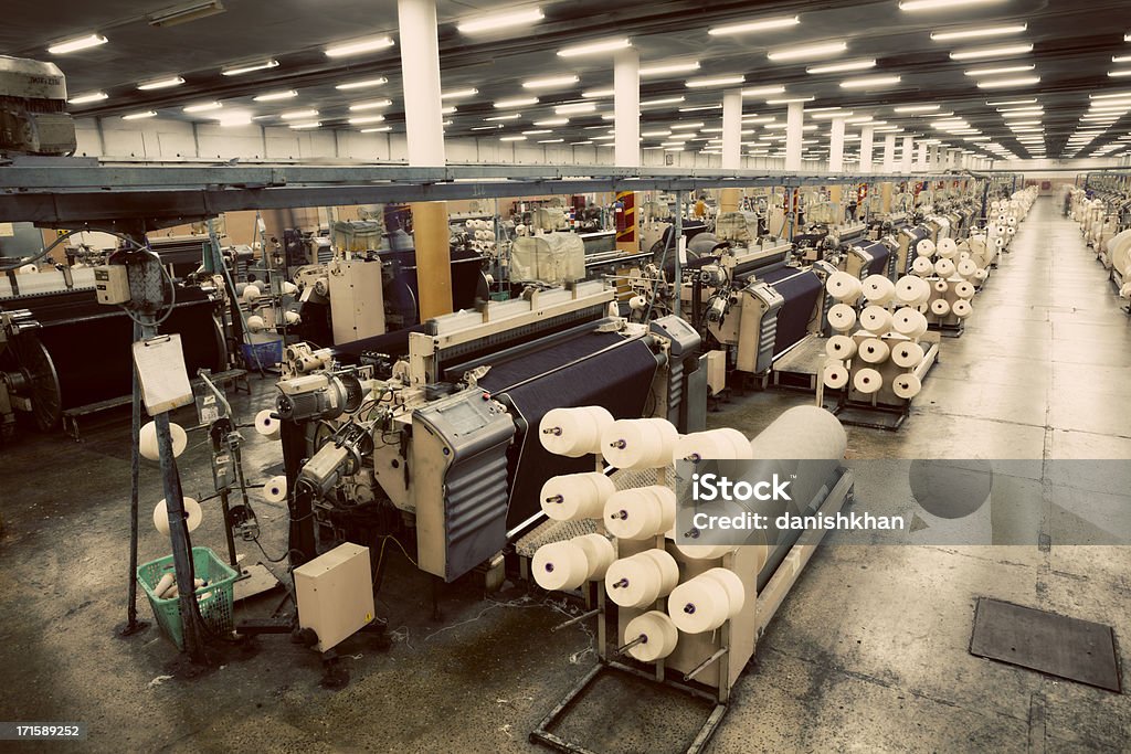 Denim Textile Industry - Weaving Jeans Fabric on Airjet Looms Weaving fabric on air jet looms in big textile weaving unit. Fiber Stock Photo