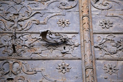 Handle on an aged painted ornament metal door Concept historical exterior design element. Low angle view