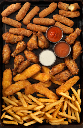 Mozzarella sticks, chicken wings, french fries and chicken fingers with 3 kinds of dip on a baking tray - Photographed on Hasselblad H3D2-39mb Camera