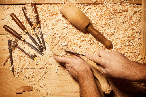 Carpenters' hands, working on a piece of wood. Professional tools on a wooden table in the workshop. Surface covered with sawdust.