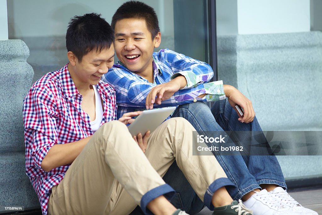 Hombre joven feliz usando tableta juntos al aire libre - Foto de stock de 20-24 años libre de derechos