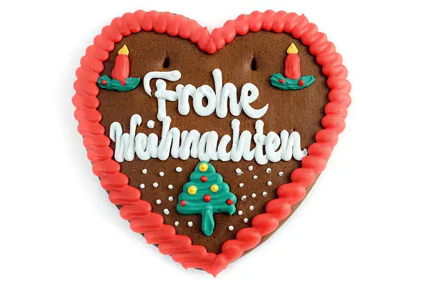 Merry Christmas (german: Frohe Weihnachten) gingerbread cookie heart in red, green white with two candles.