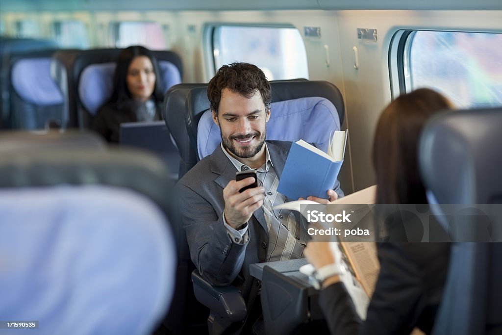 Geschäftsmann liest ein Buch auf dem Zug und mit Handy - Lizenzfrei Colleague Stock-Foto