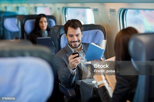 Geschäftsmann Liest Ein Buch Auf Dem Zug Und Mit Handy Stockfoto und mehr Bilder von Colleague