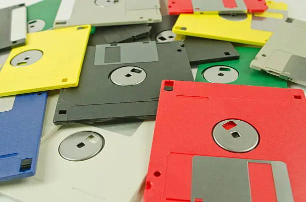 A stack of different colored computer floppy disks. Selective focus on the front disks.
